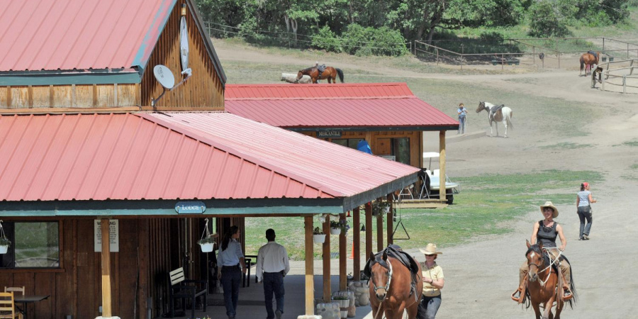 Red roof buildings at Parelli Ranch with horses & people strolling by.