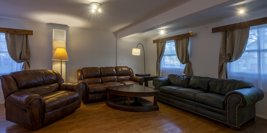 Great room with large recliner to the left; couch & table in the distance; large couch to the right.